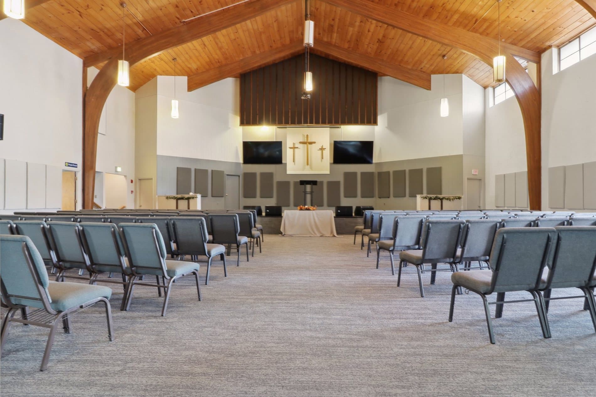 Bright sanctuary with rows of chairs and a timber ceiling