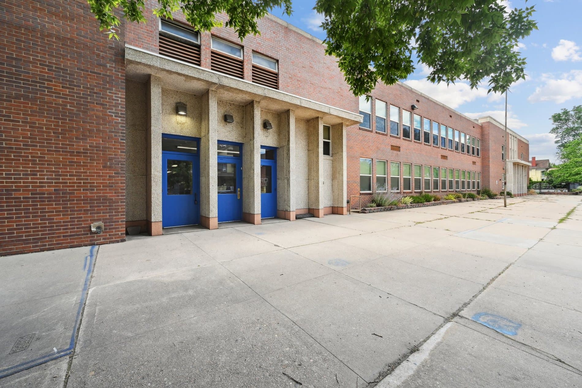 Brick school building with blue doors and a broad entrance