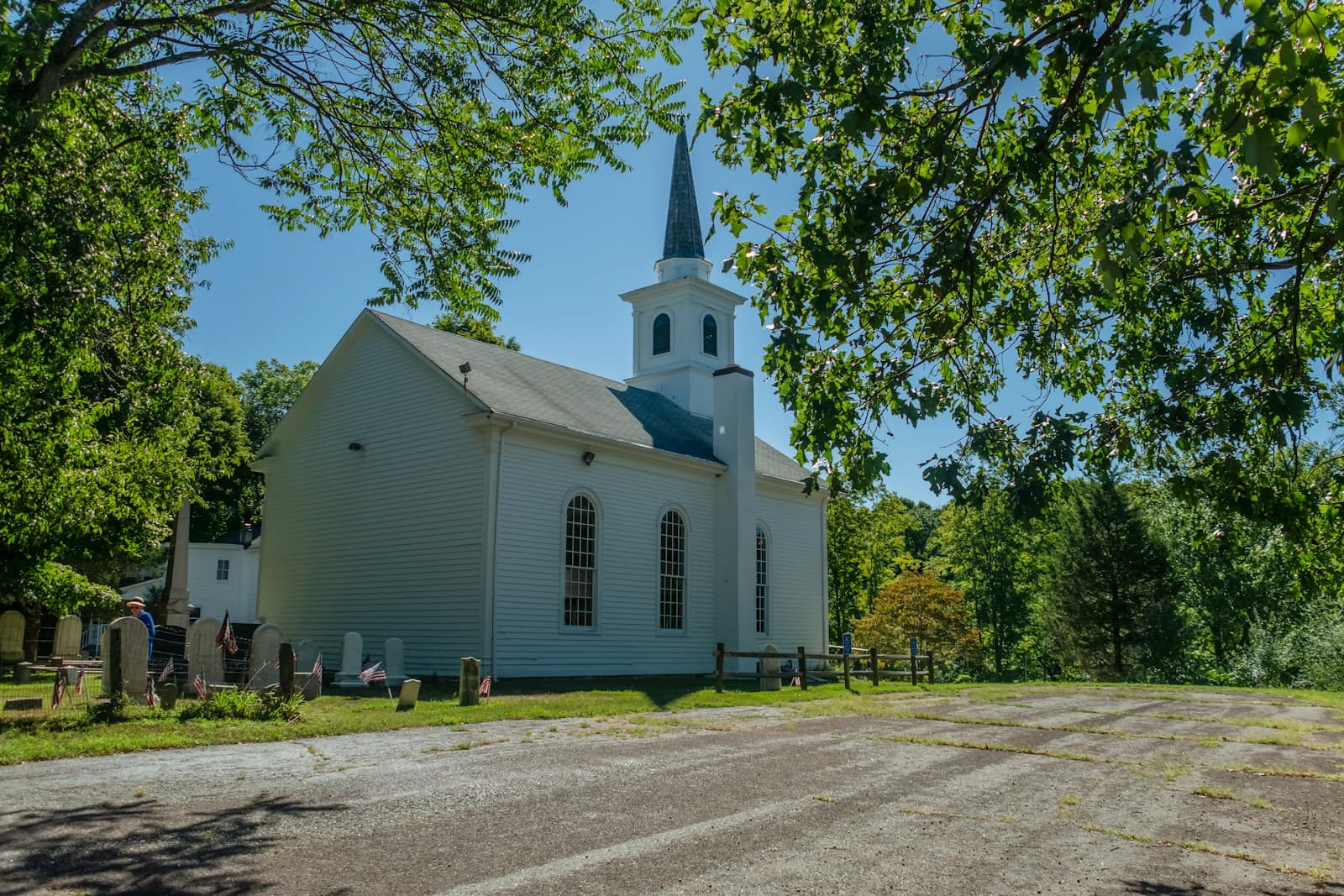 White church building with a steeple among trees