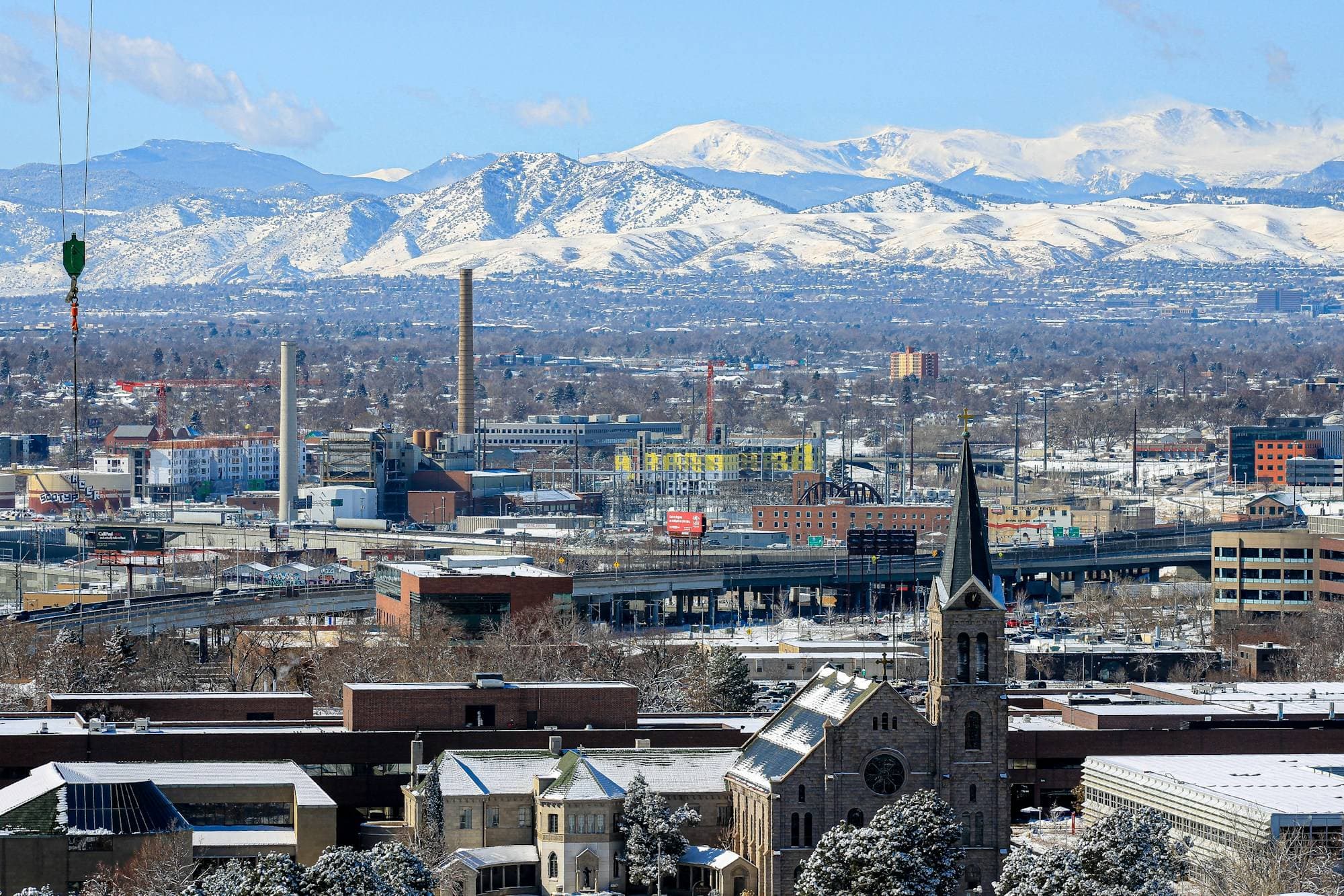 Denver neighborhood with a church steeple in front of the snow-covered Front Range