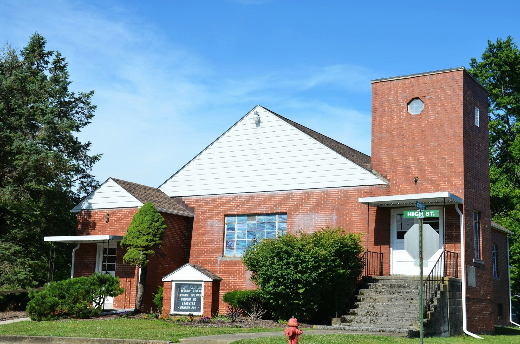 Red brick neighborhood church with a bell tower and front steps